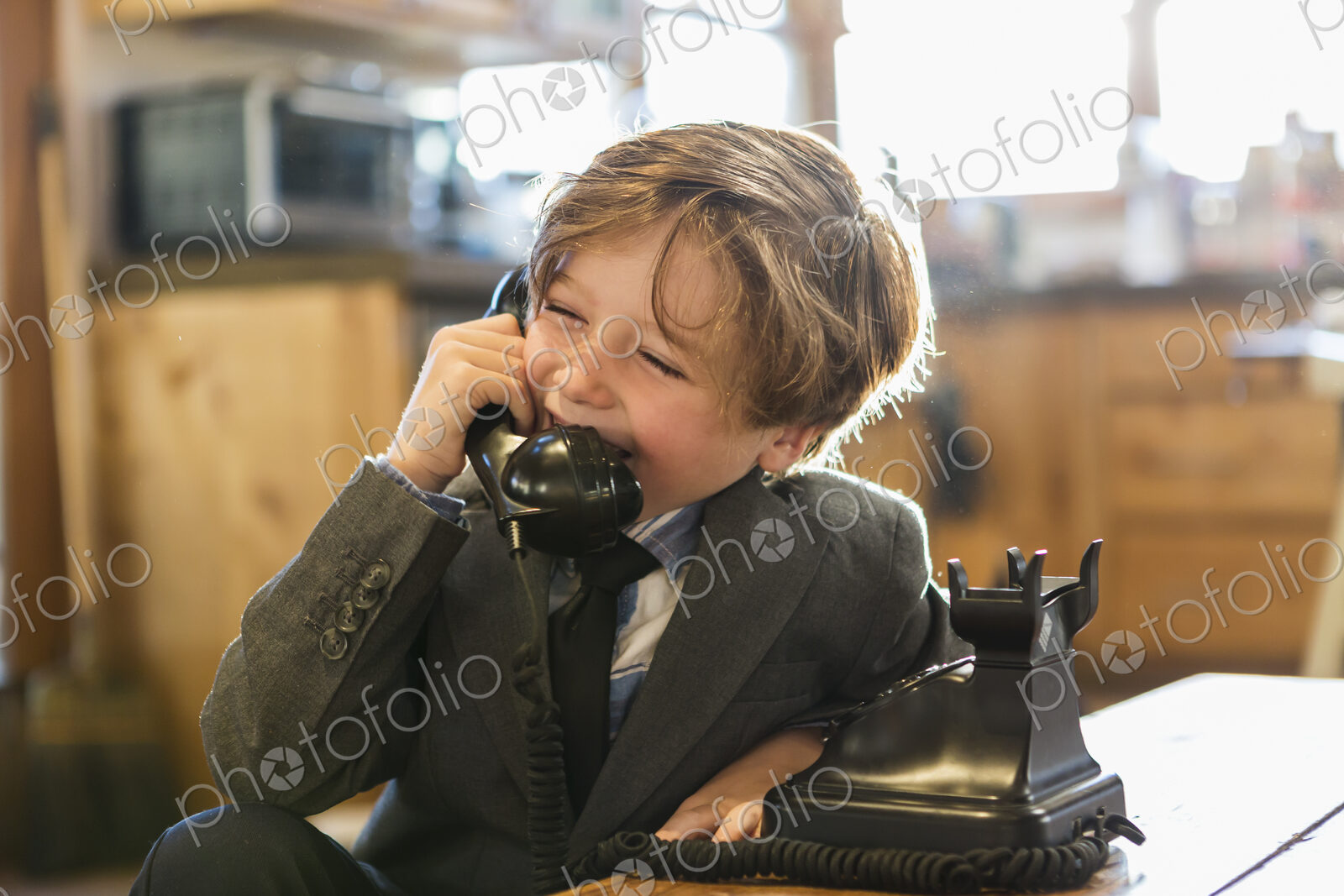 A six year old boy in a suit and tie talking on a old vintage phone at home