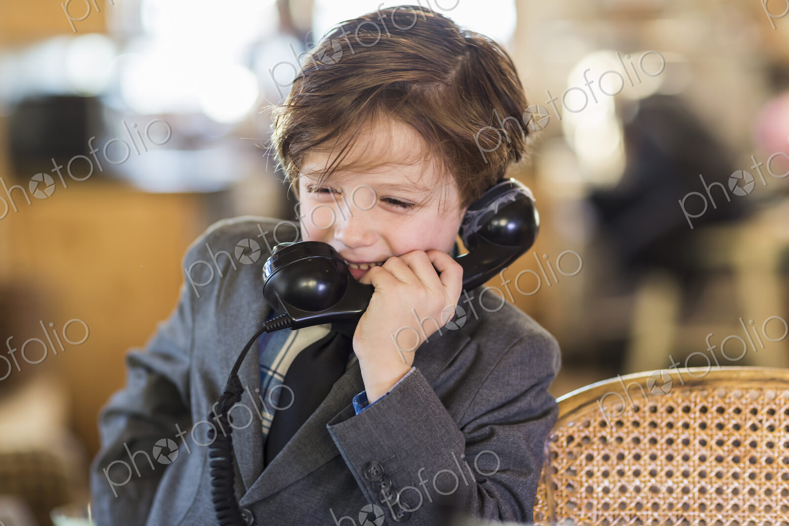 A six year old boy in a suit talking on a old vintage phone at home