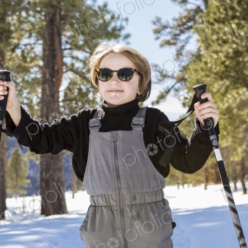 A six year old boy in woodland holding ski poles