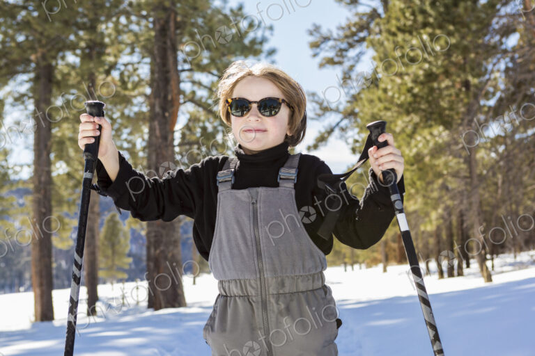 A six year old boy in woodland holding ski poles
