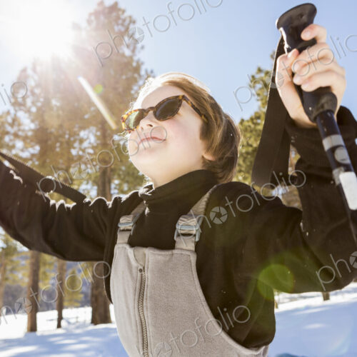A six year old boy in woodland holding ski poles