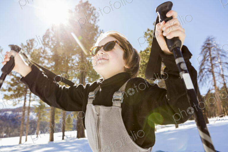 A six year old boy in woodland holding ski poles