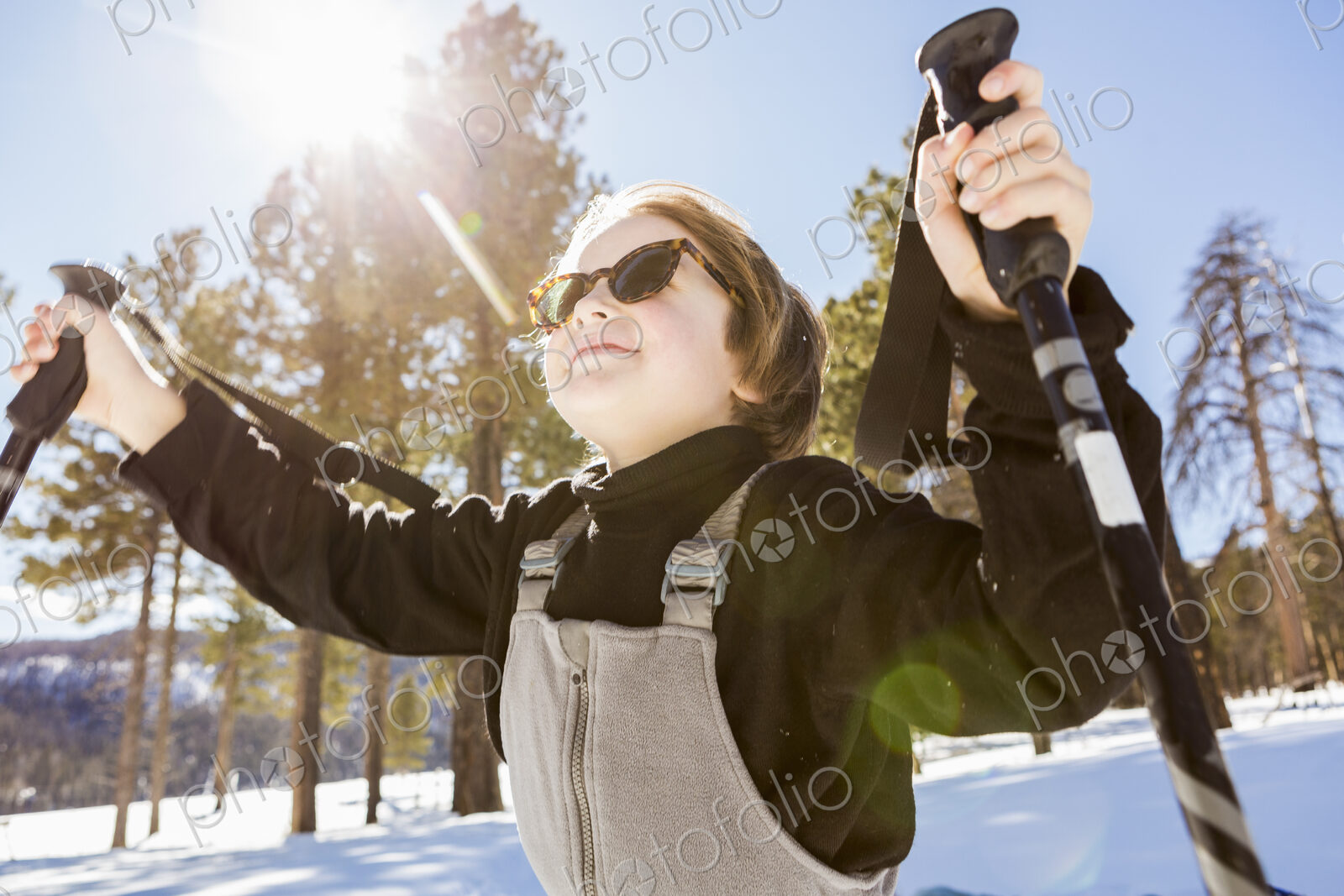 A six year old boy in woodland holding ski poles