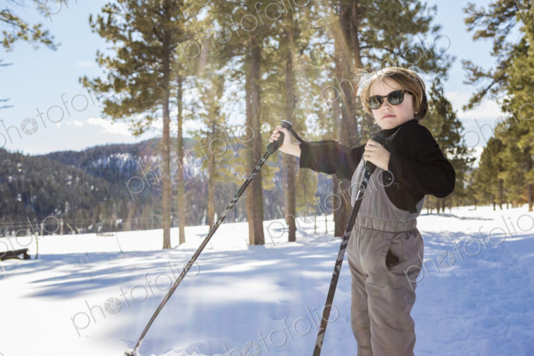 A six year old boy in woodland holding ski poles