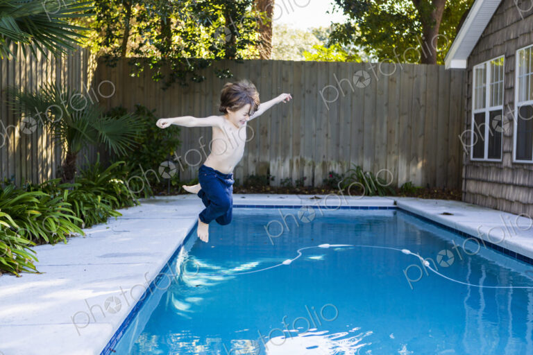A six year old boy leaping into a swimming pool