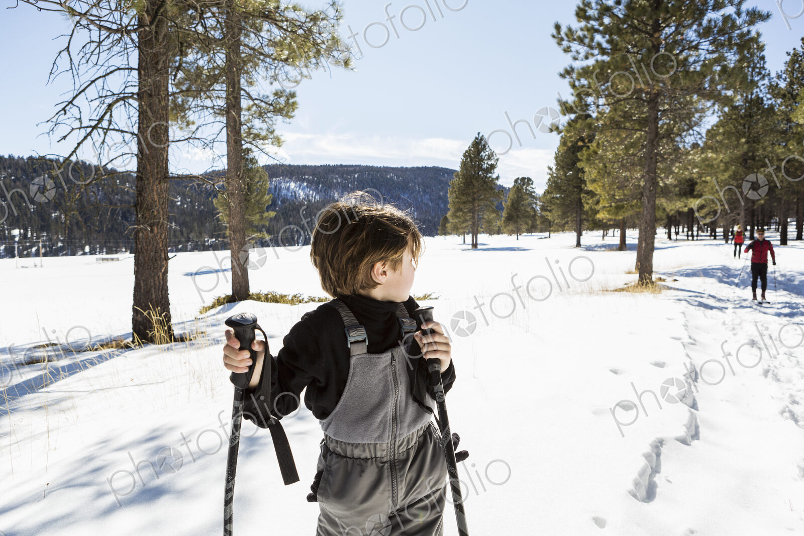 A six year old boy on snow shoes among trees.