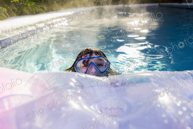 A six year old boy playing in a heated pool