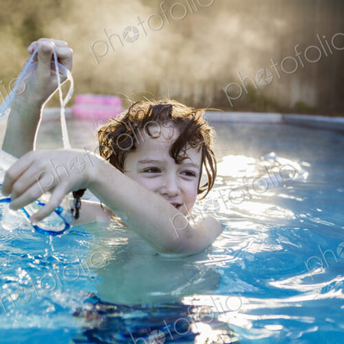 A six year old boy playing in a warm pool, steam rising. A six year old boy playing in a warm pool, steam rising.