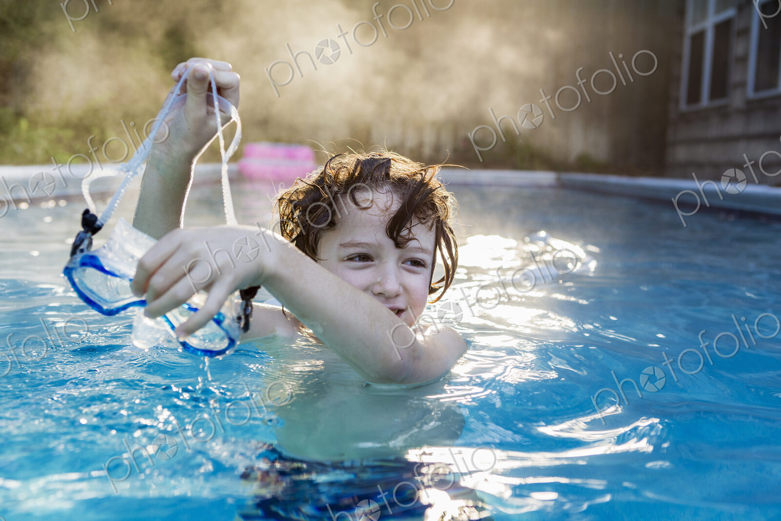 A six year old boy playing in a warm pool, steam rising.