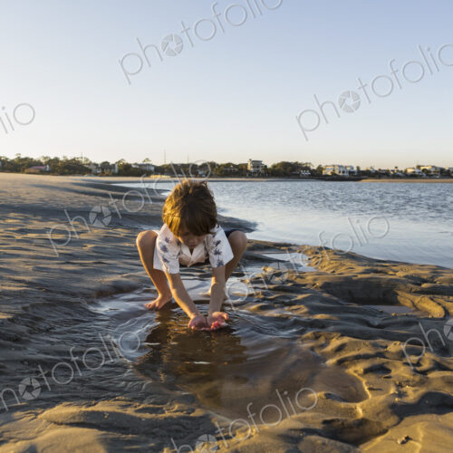 A six year old boy playing on the beach in a pool of water A six year old boy playing on the beach in a pool of water