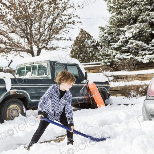 A six year old boy shoveling snow in driveway