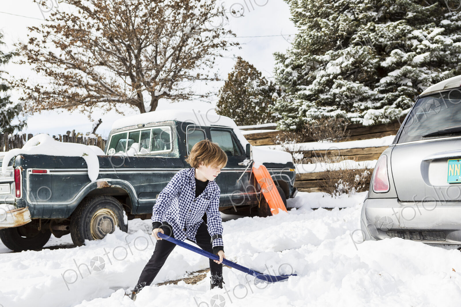 A six year old boy shoveling snow in driveway