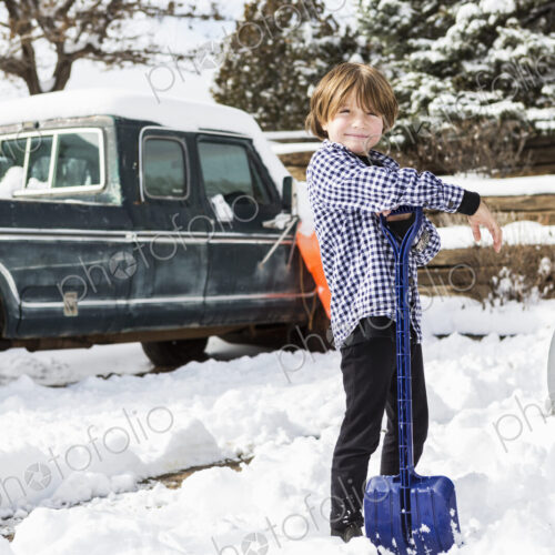 A six year old boy shoveling snow in driveway