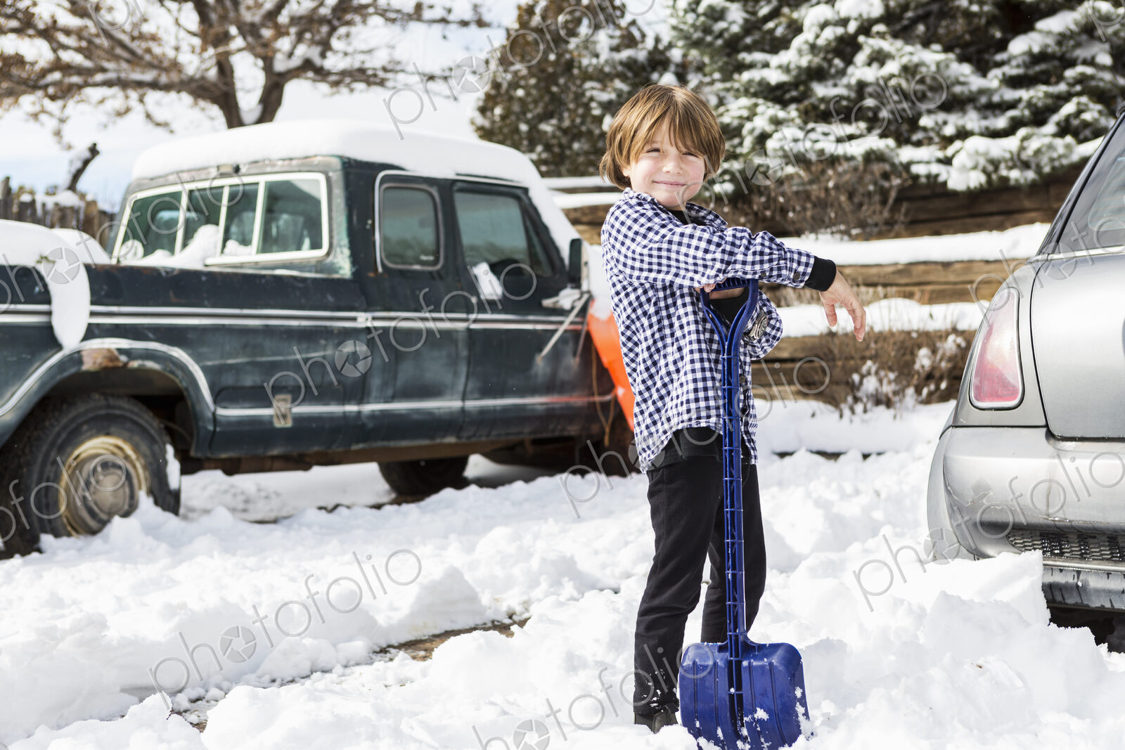 A six year old boy shoveling snow in driveway