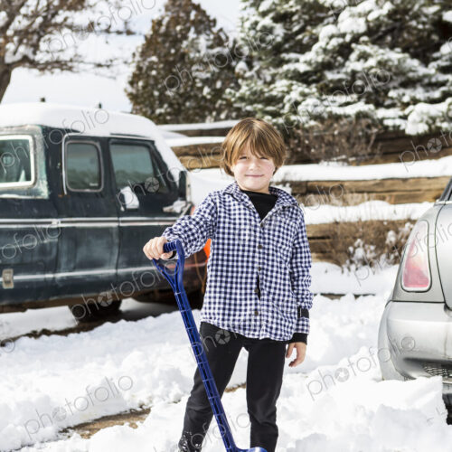 A six year old boy shoveling snow in driveway