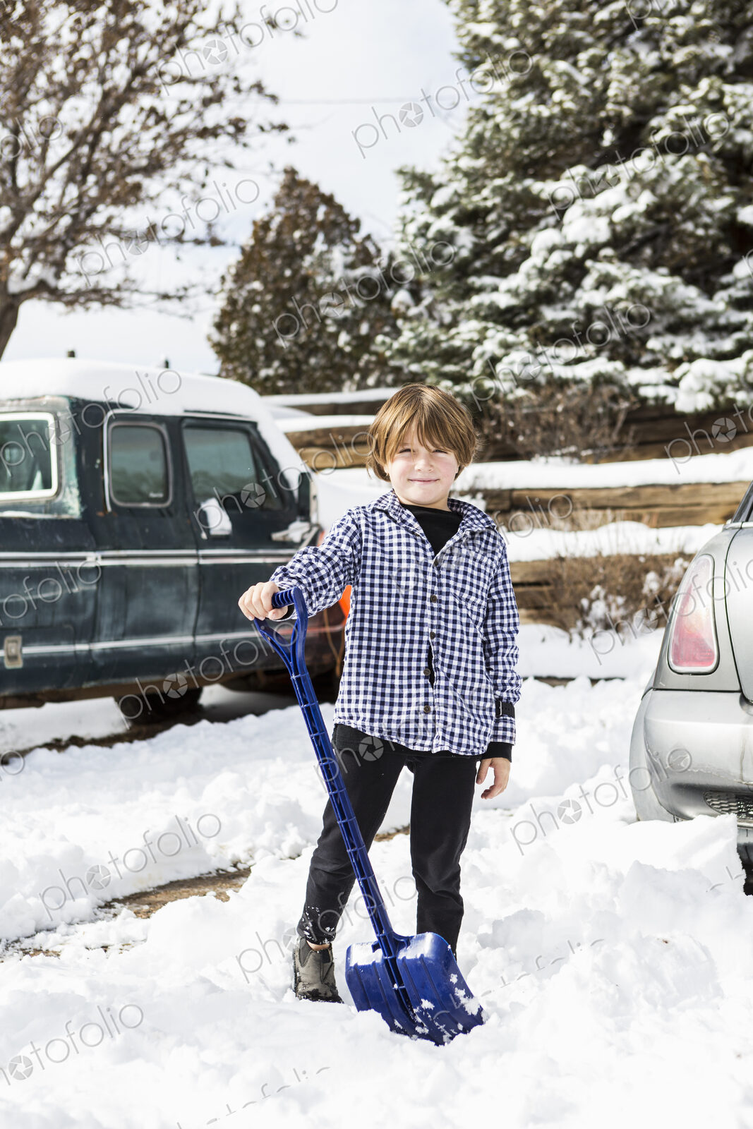 A six year old boy shoveling snow in driveway