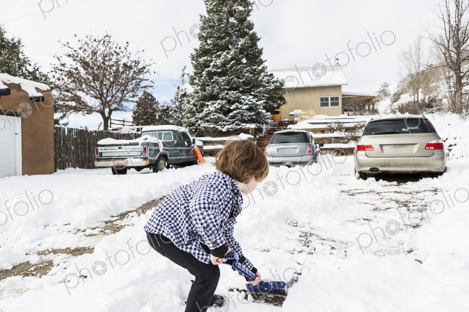 A six year old boy shoveling snow in driveway