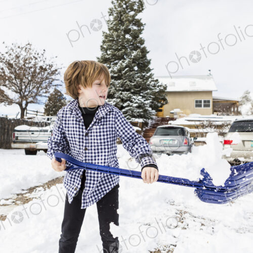 A six year old boy shoveling snow in driveway