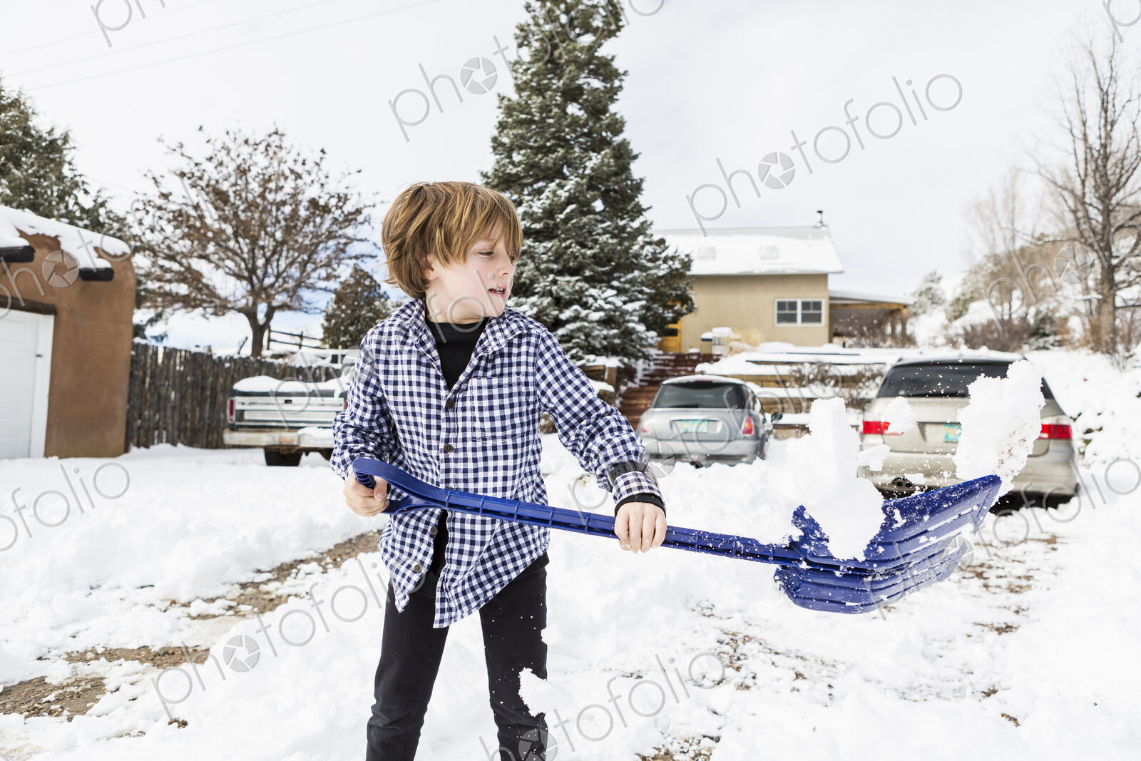 A six year old boy shoveling snow in driveway