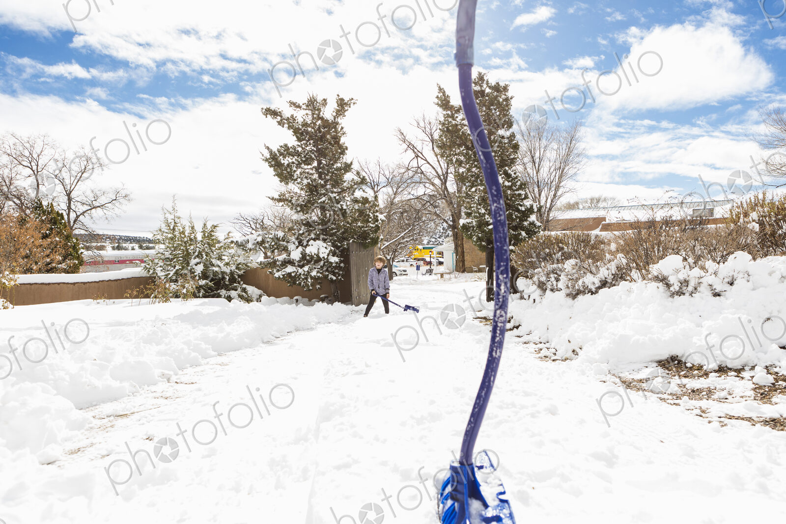 A six year old boy shoveling snow in driveway