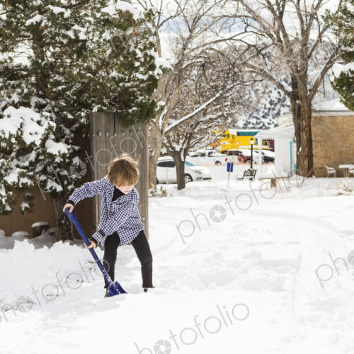 A six year old boy shoveling snow in driveway