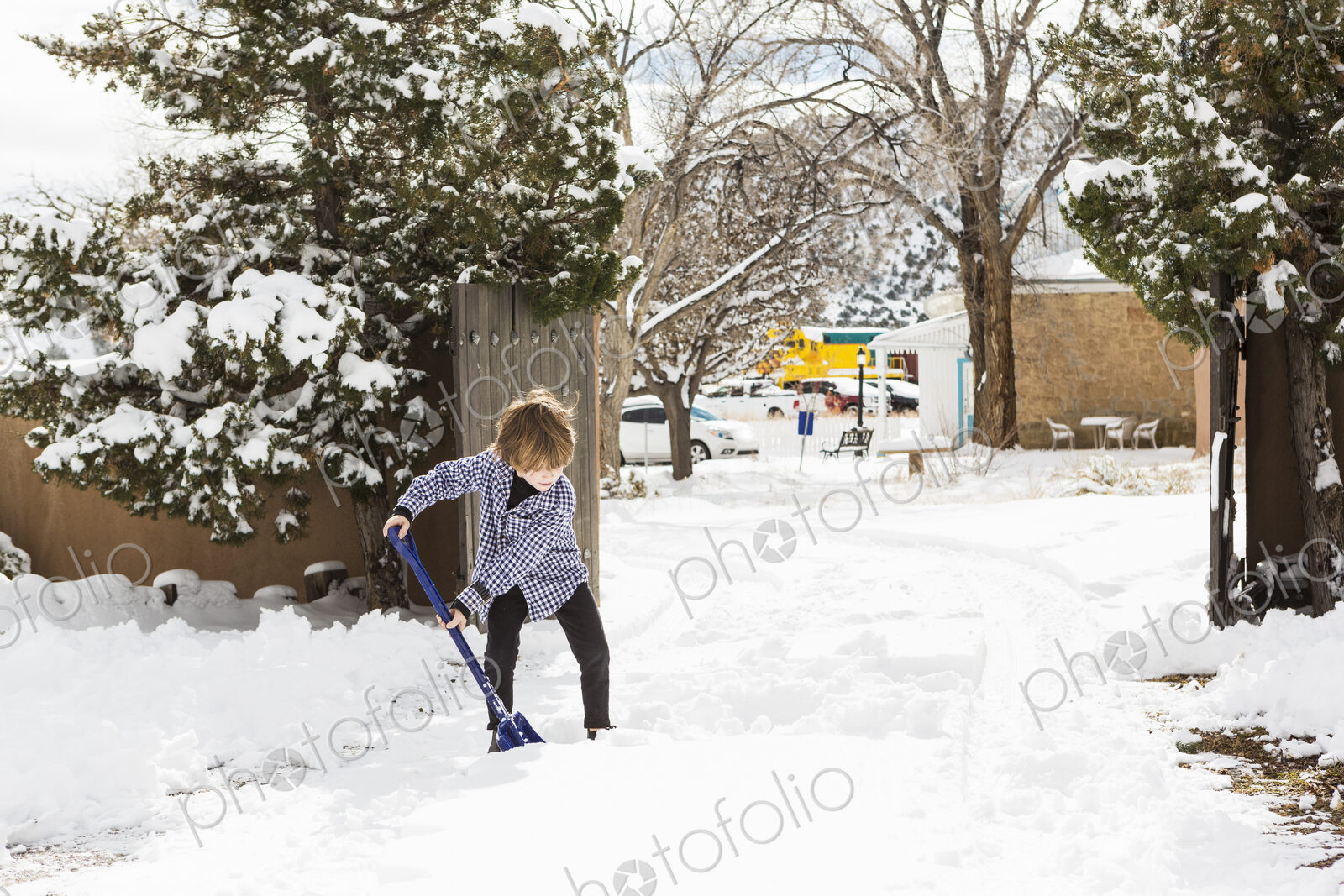 A six year old boy shoveling snow in driveway