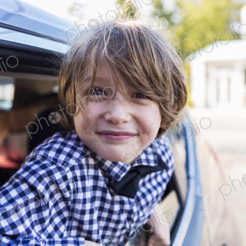 A six year old boy smiling at camera, looking out of car window A six year old boy smiling at camera, looking out of car window