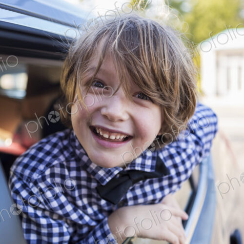 A six year old boy smiling at camera, looking out of car window A six year old boy smiling at camera, looking out of car window
