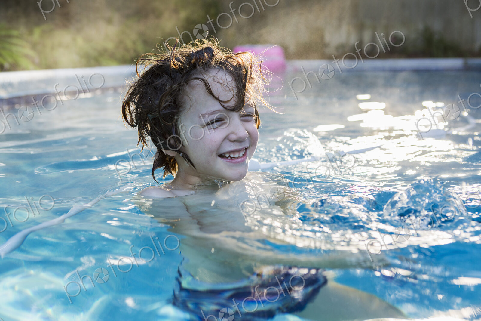 A six year old boy swimming in a warm pool.