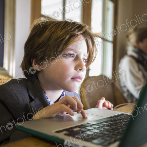 A six year old boy typing on a laptop at home