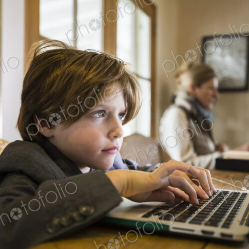A six year old boy typing on a laptop at home