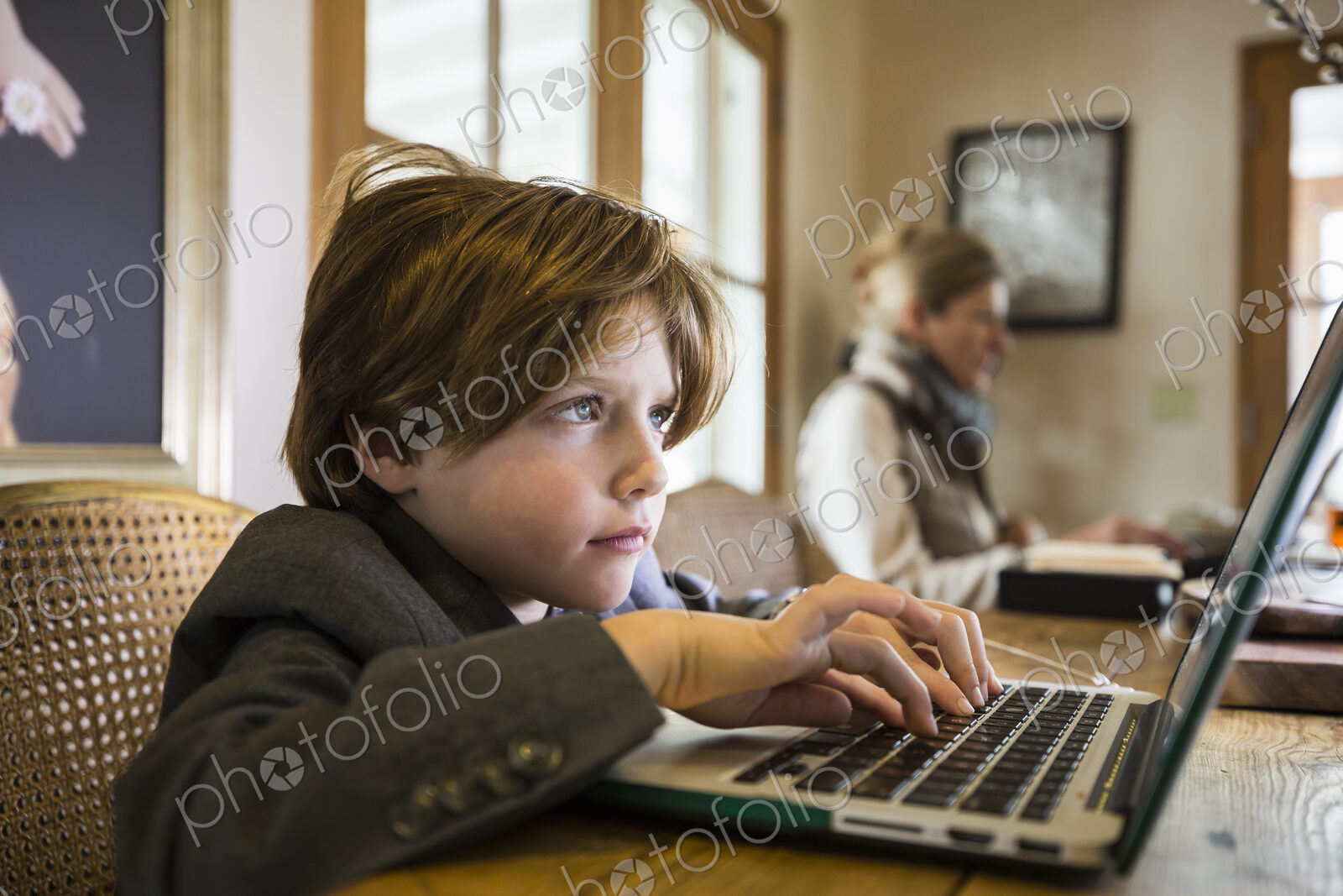 A six year old boy typing on a laptop at home