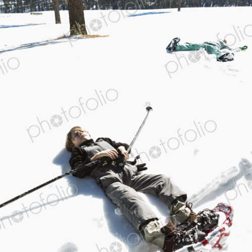 A six year old boy wearing snow shoes, lying down on his back in snow A six year old boy wearing snow shoes, lying down on his back in snow
