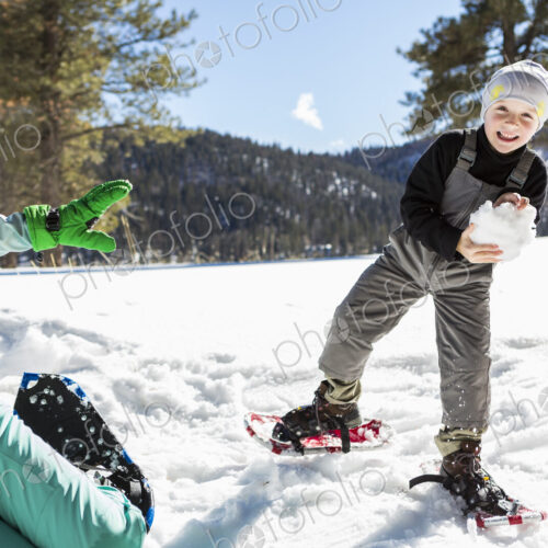 A six year old boy with snow shoes holding a large snowball. A six year old boy with snow shoes holding a large snowball.