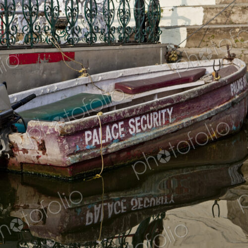 A small boat with an outboard motor moored at the steps of a palace terrace and…