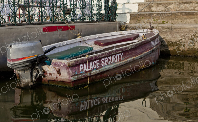A small boat with an outboard motor moored at the steps of a palace terrace and…