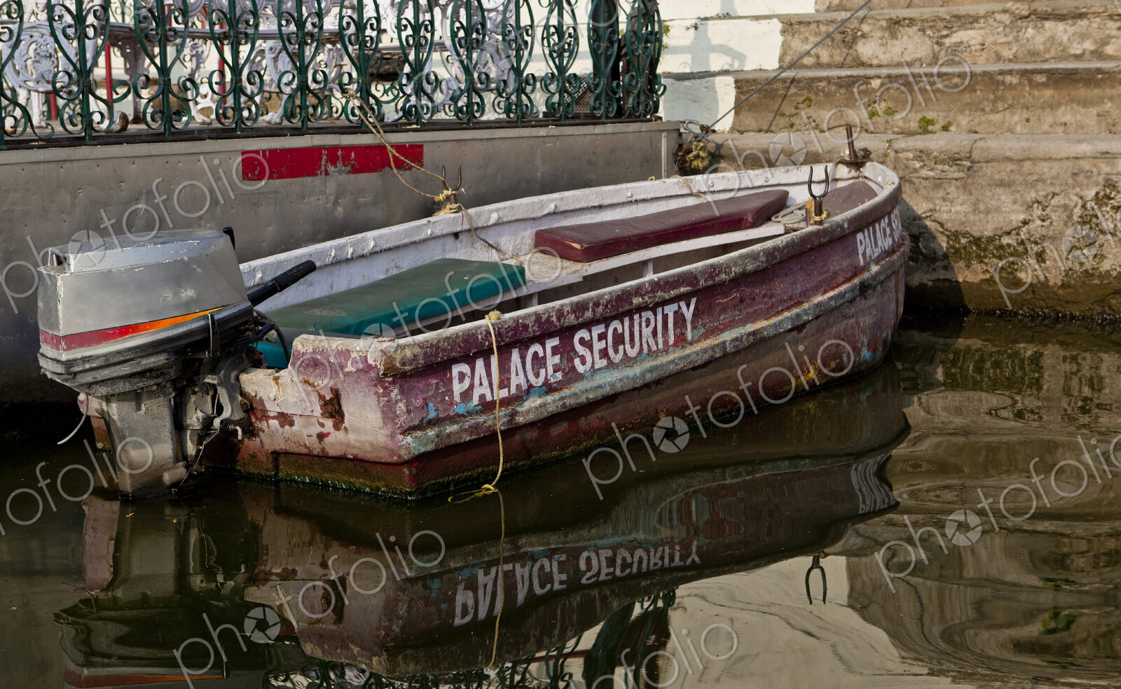 A small boat with an outboard motor moored at the steps of a palace terrace and…