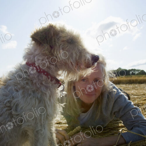 A small dog sitting and looking into the distance. A woman beside him on the group.… A small dog sitting and looking into the distance. A woman beside him on the group.…