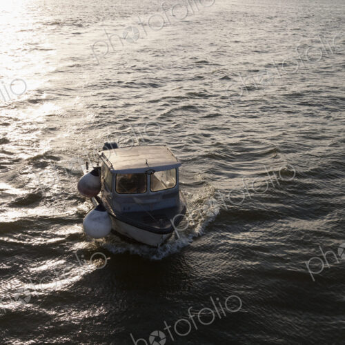 A small fishing boat on the sea at sunset, elevated view.