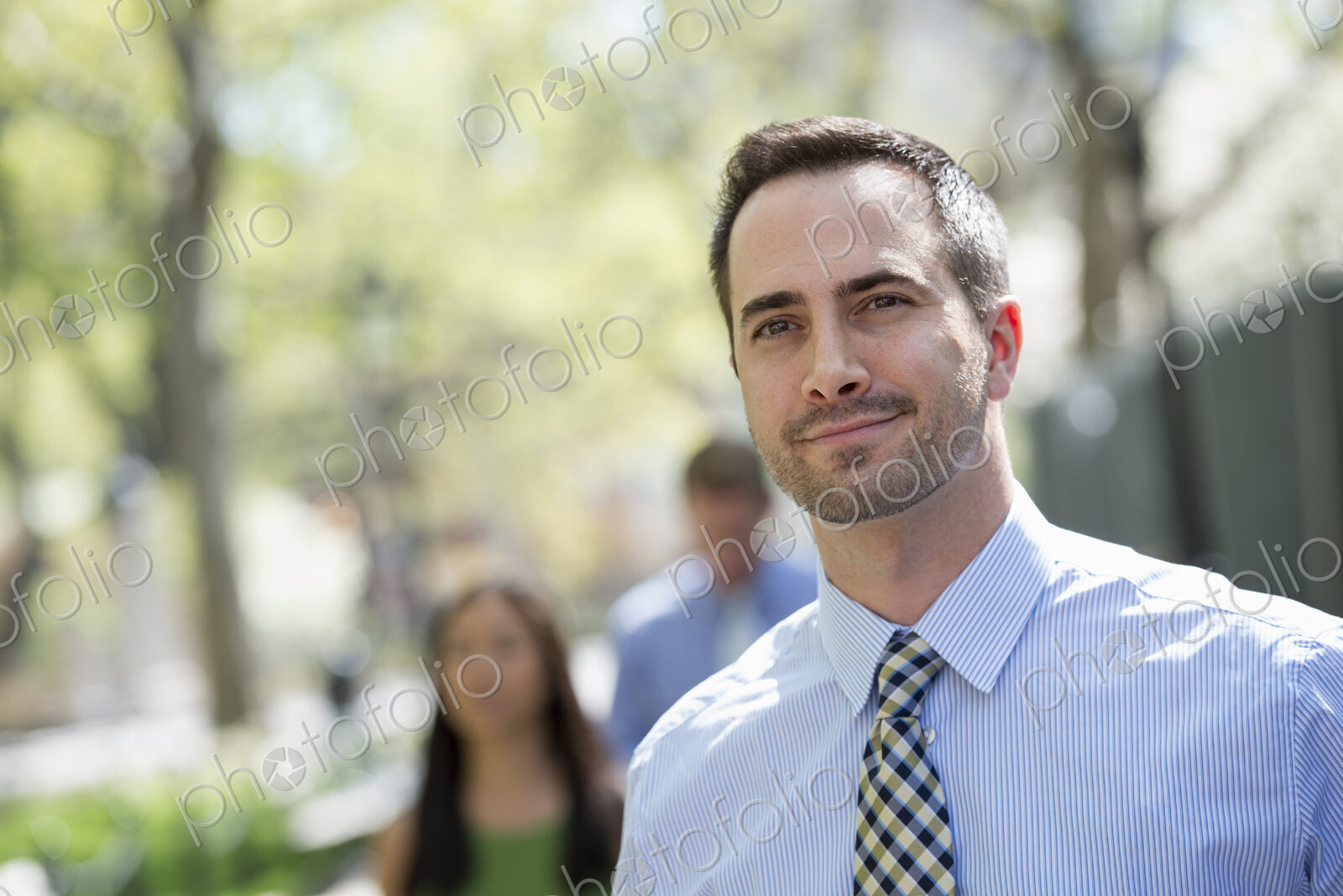 A small group of people, a businesswoman and two businessmen outdoors in the city.