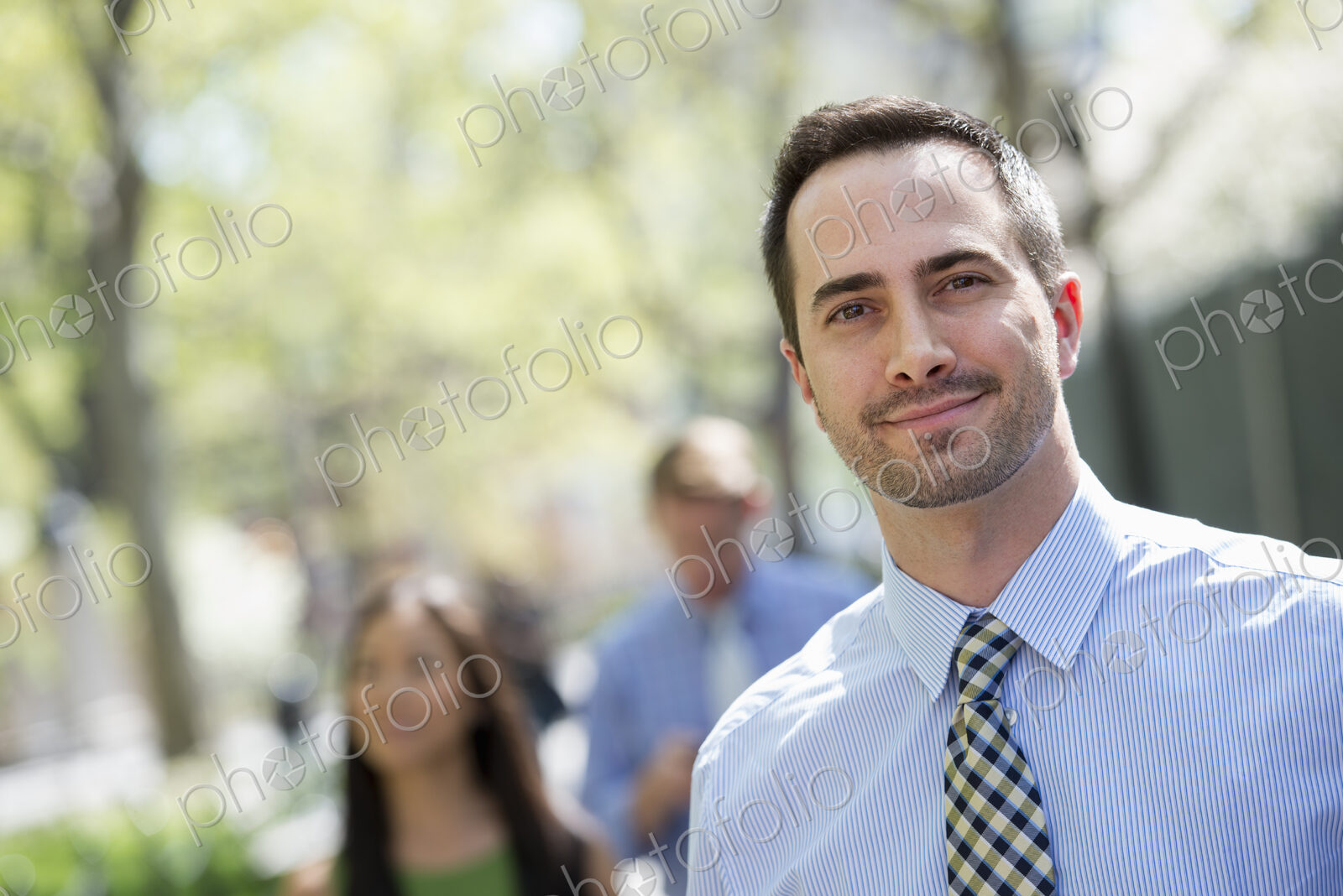 A small group of people, a businesswoman and two businessmen outdoors in the city.