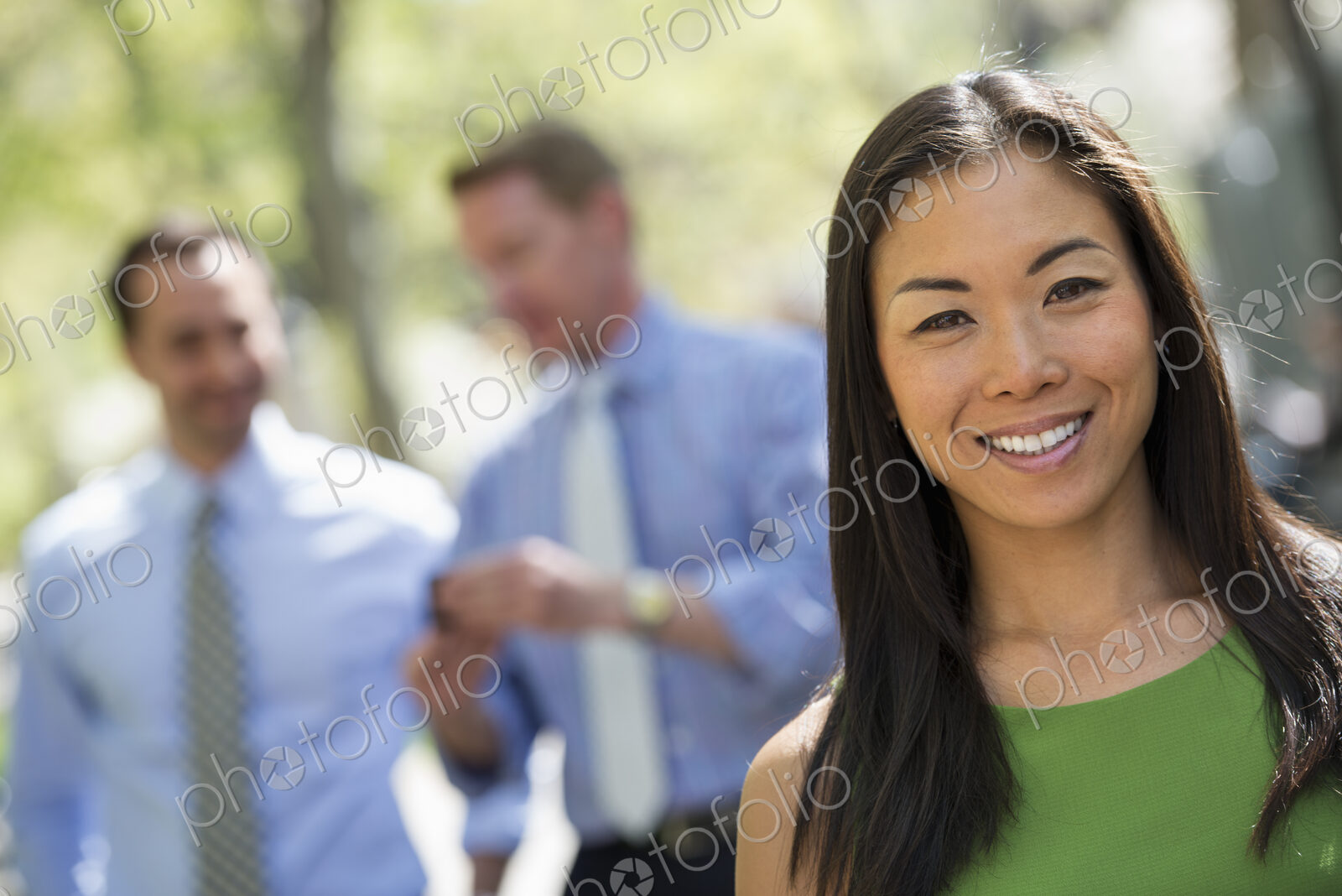 A small group of people, a businesswoman and two businessmen outdoors in the city.