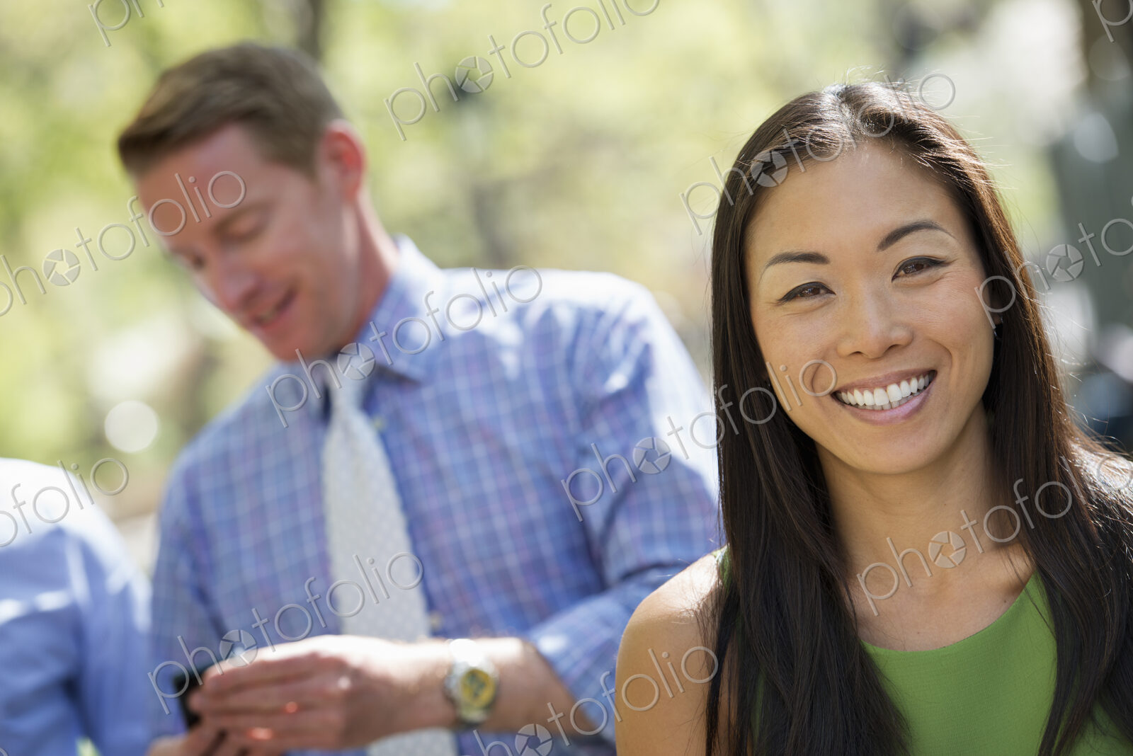 A small group of people, a businesswoman and two businessmen outdoors in the city.