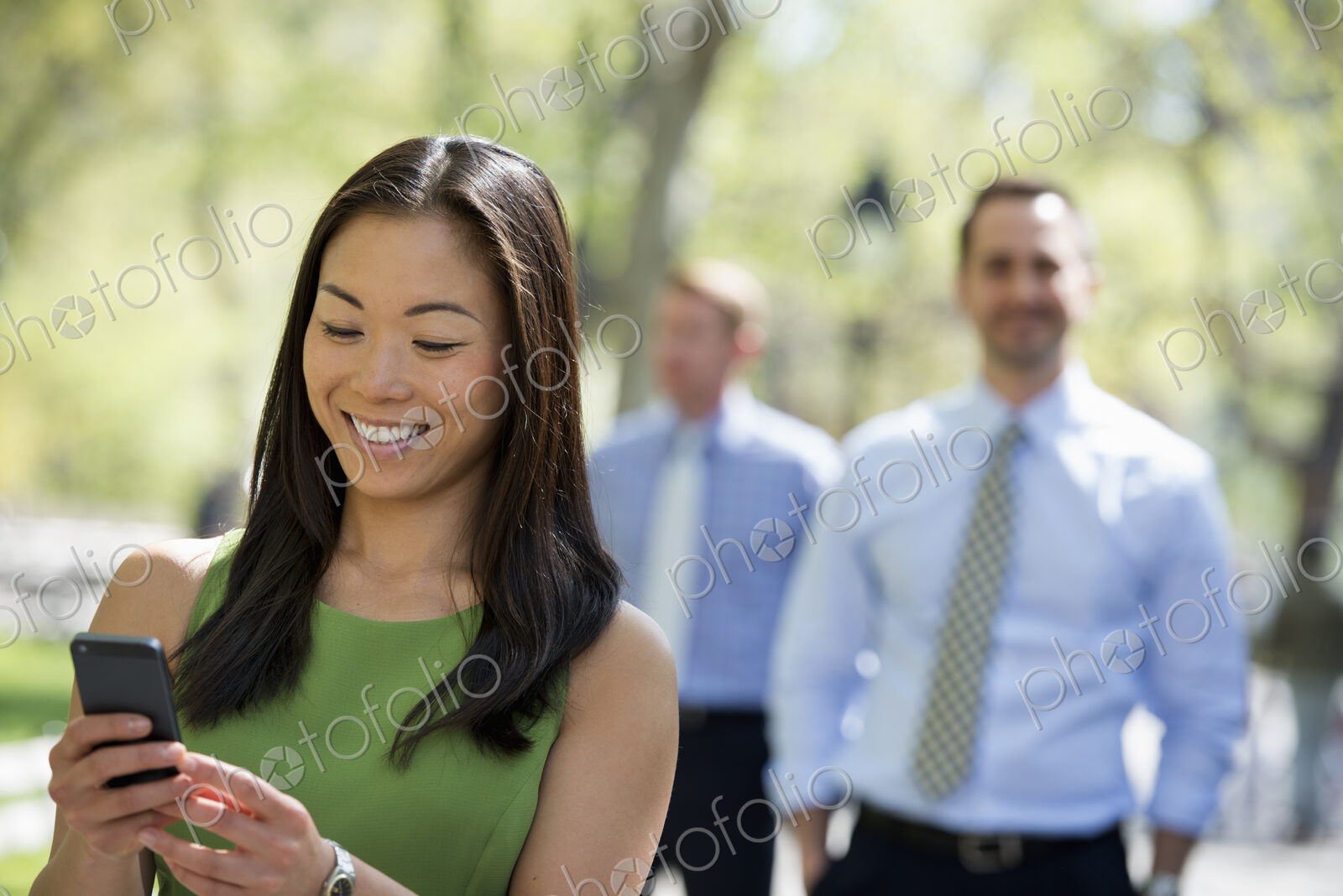 A small group of people, a businesswoman and two businessmen outdoors in the city.