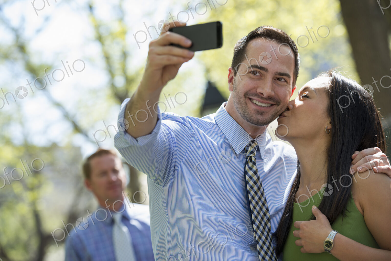 A small group of people, a businesswoman and two businessmen outdoors in the city.
