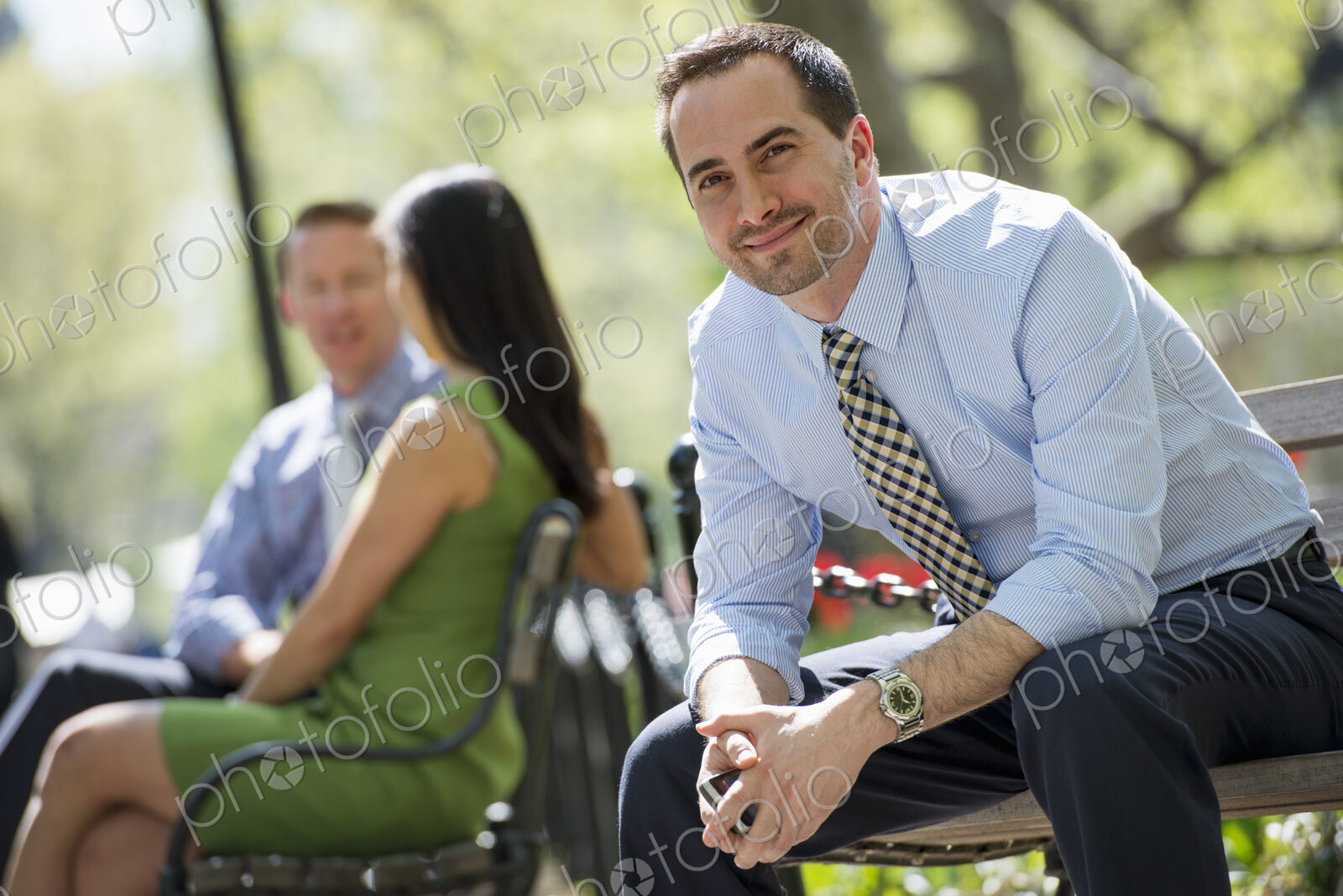 A small group of people, a businesswoman and two businessmen outdoors in the city.