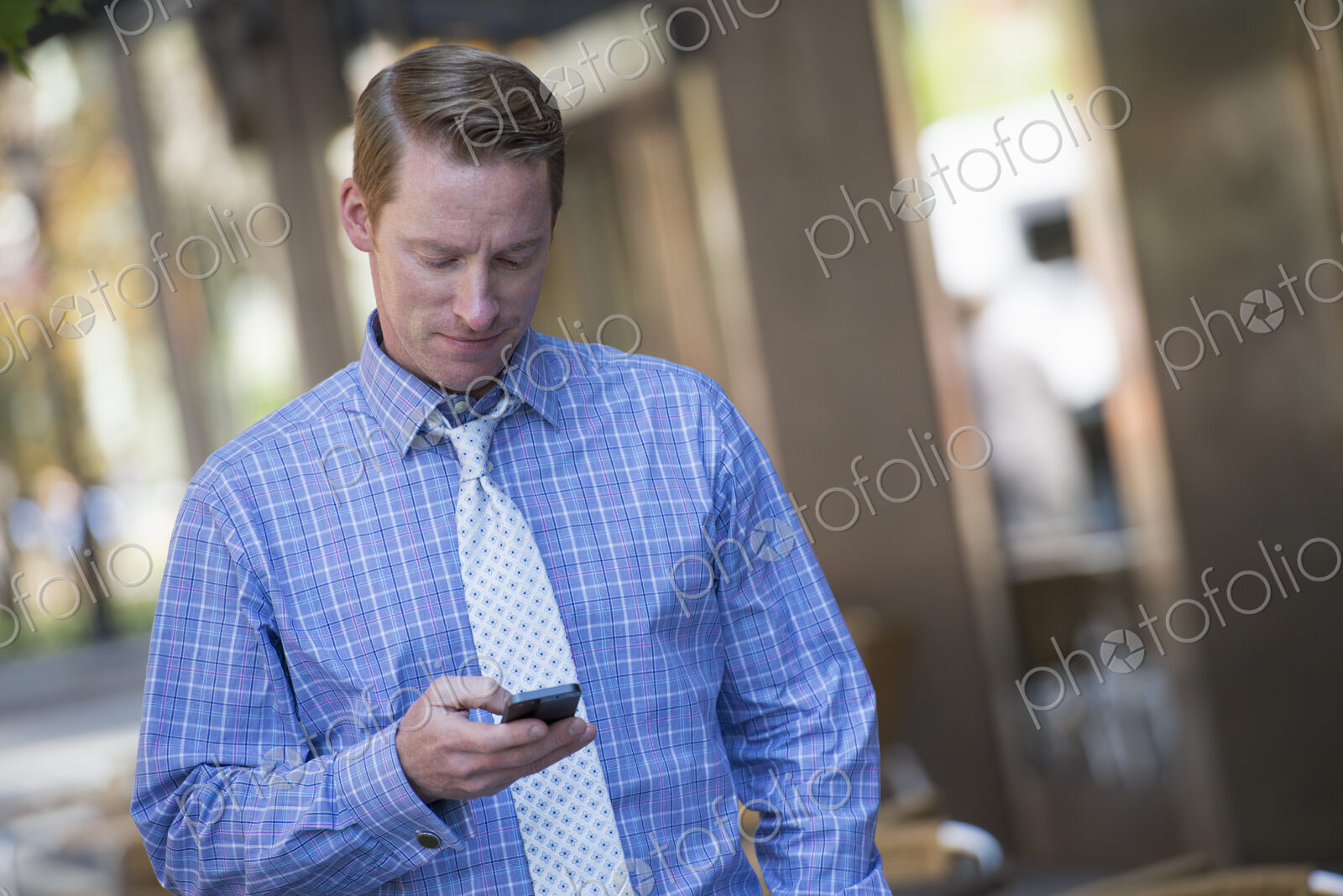 A small group of people, a businesswoman and two businessmen outdoors in the city.