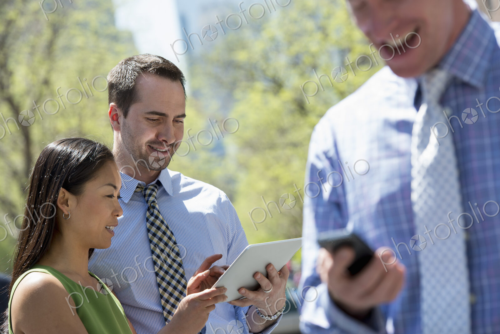 A small group of people, a businesswoman and two businessmen outdoors in the city.…