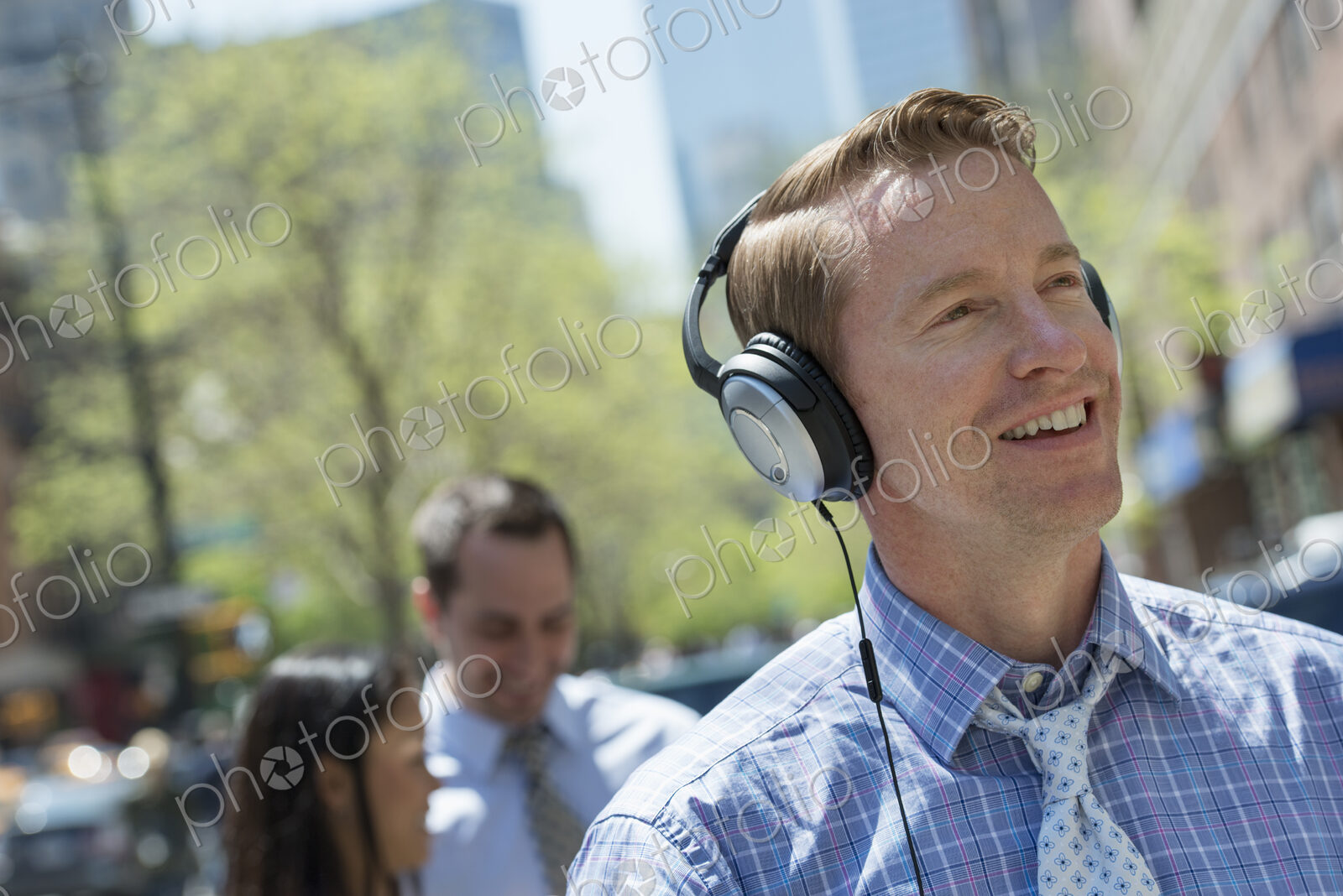 A small group of people outdoors in the city. A man listening to music on his…