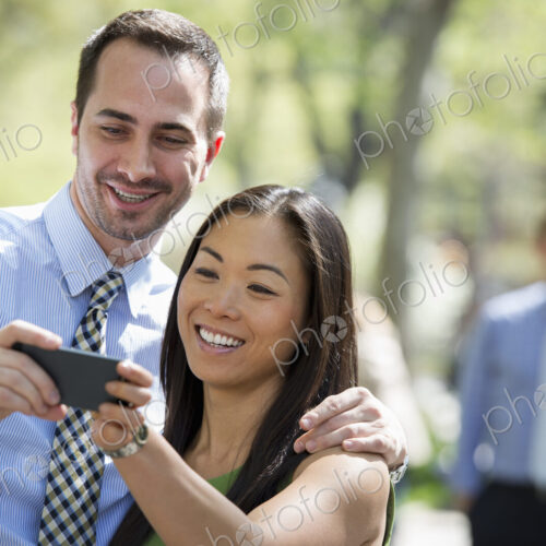 A small group of people. A couple with a smart phone, side by side. A man in the… A small group of people. A couple with a smart phone, side by side. A man in the…